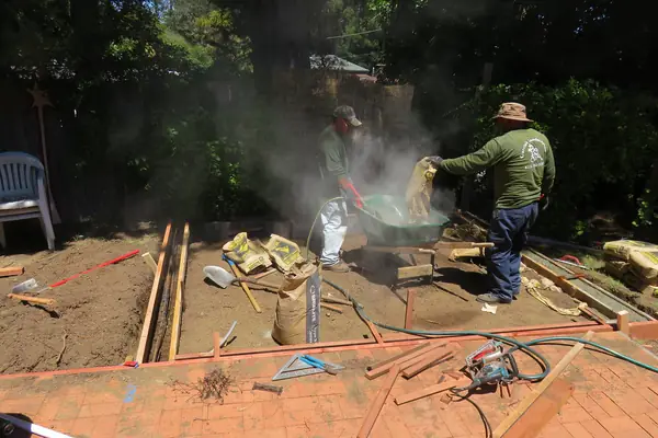 Mixing bagged concrete beside backyard pad forms
