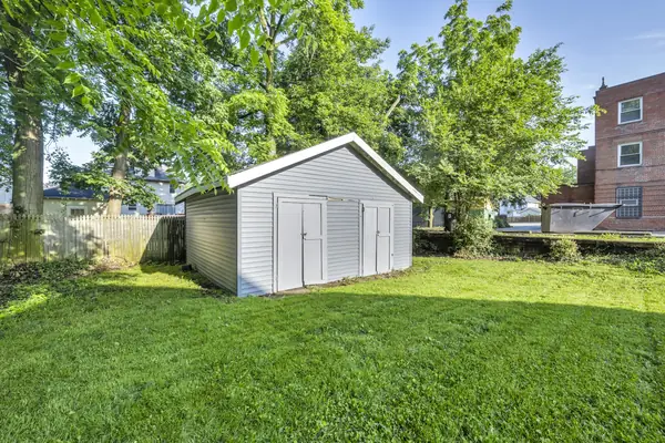Gray backyard shed with double doors on a grass lawn