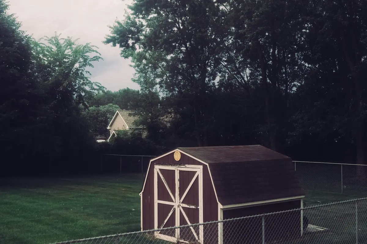 Small barn-style shed inside a fenced backyard