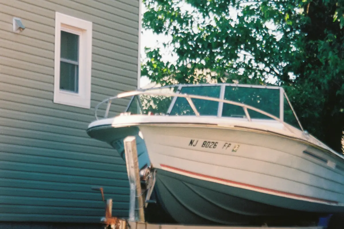 Motorboat on its trailer parked on grass beside a house