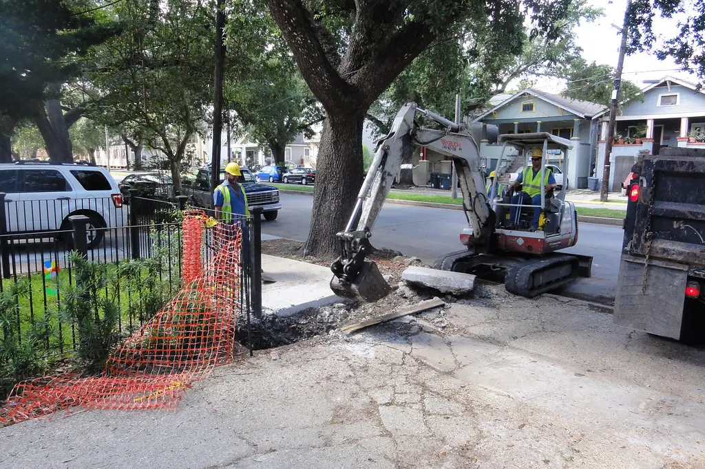Mini excavator breaking out an old driveway apron at the street