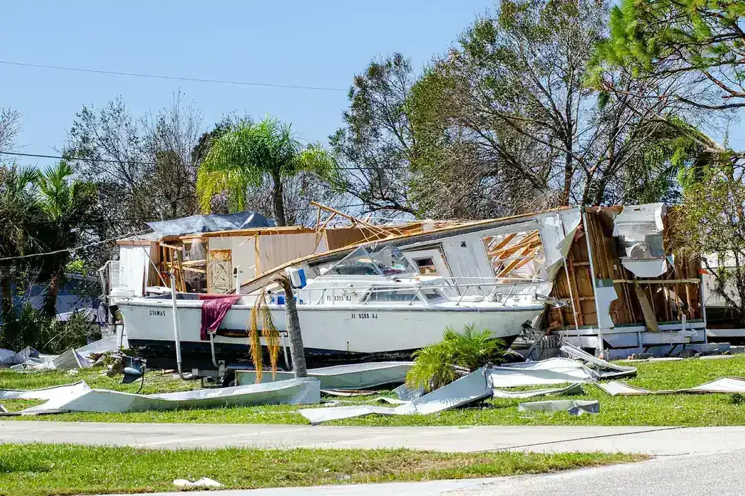 Boat and wrecked building debris pushed onto a lawn by a hurricane