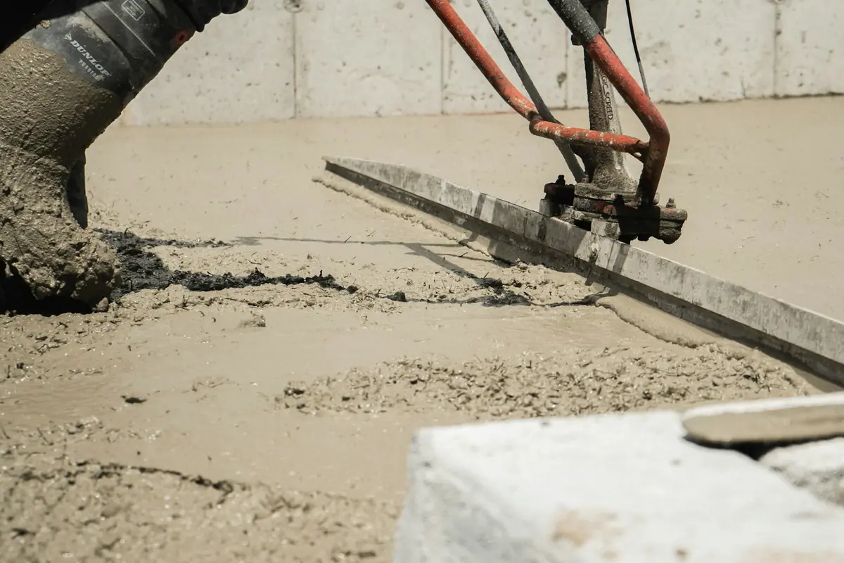 Worker running a power screed across freshly placed concrete