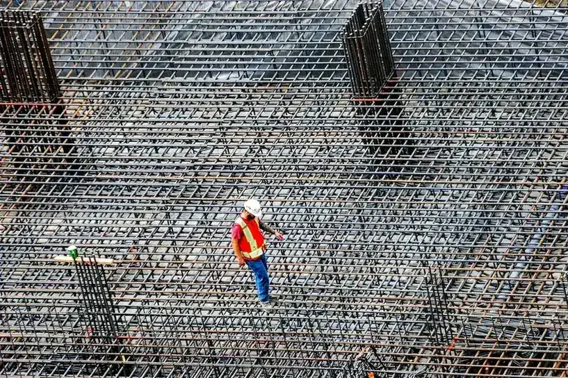 Construction worker walking a large tied rebar mat before a pour