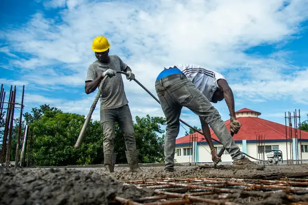 Workers spreading concrete over rebar
