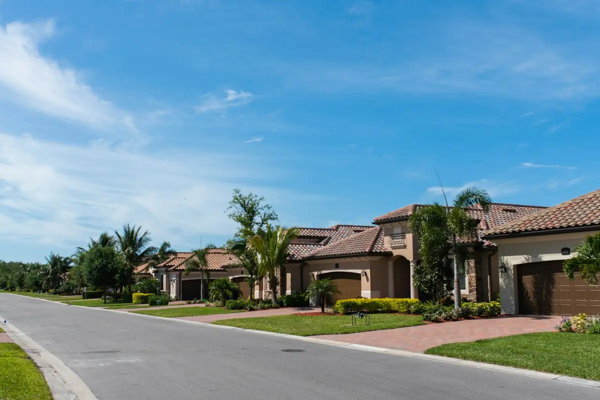 Street of stucco homes with tile roofs, palm trees and paver driveways