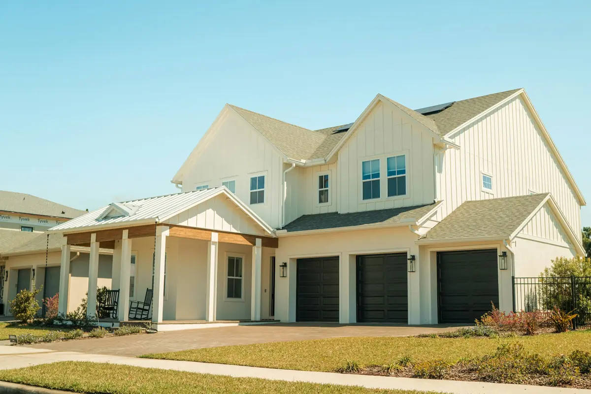 White two-story house with a three-car garage and concrete drive
