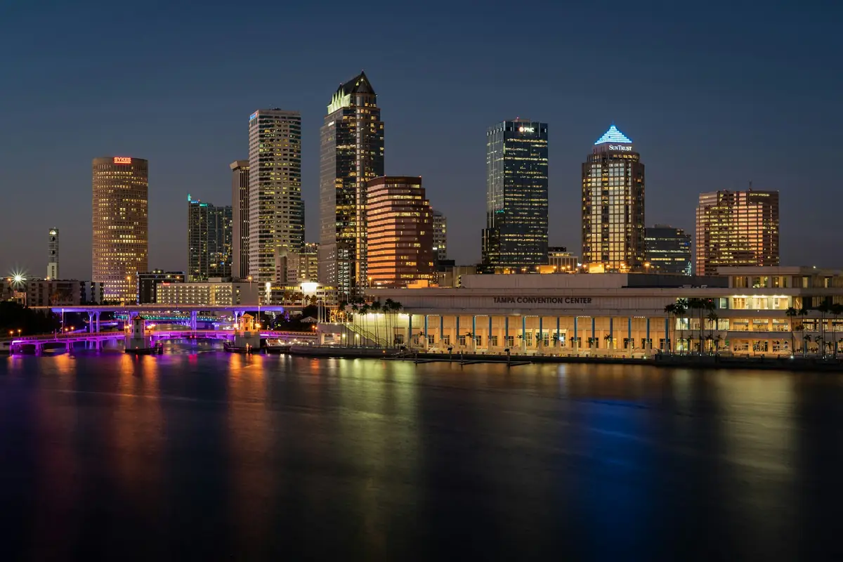 City skyline and a waterfront convention hall lit up at night over the water
